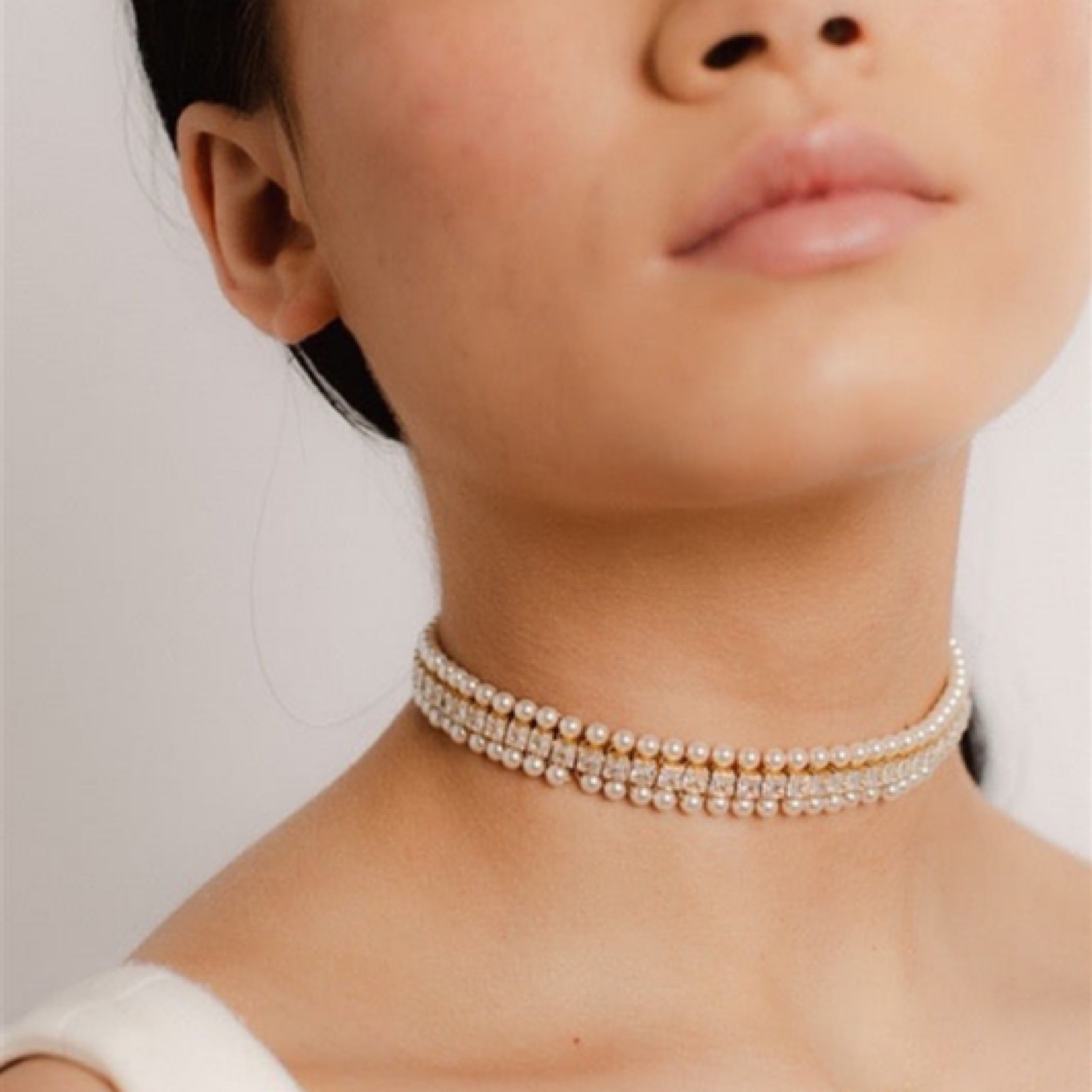 A classic petite pearl choker with rose store gold crystals at center echoed by rose gold color spacer beads and rose gold toggle clasp